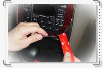 A person is putting a red tape on a car radio using an Accessories for car.