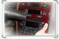 A person is using an Interior car kit to clean the radio in a car.